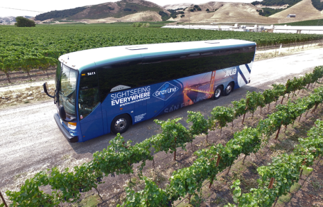 a Gray Line tour bus parked on the side of a road in a Mendocino vineyard